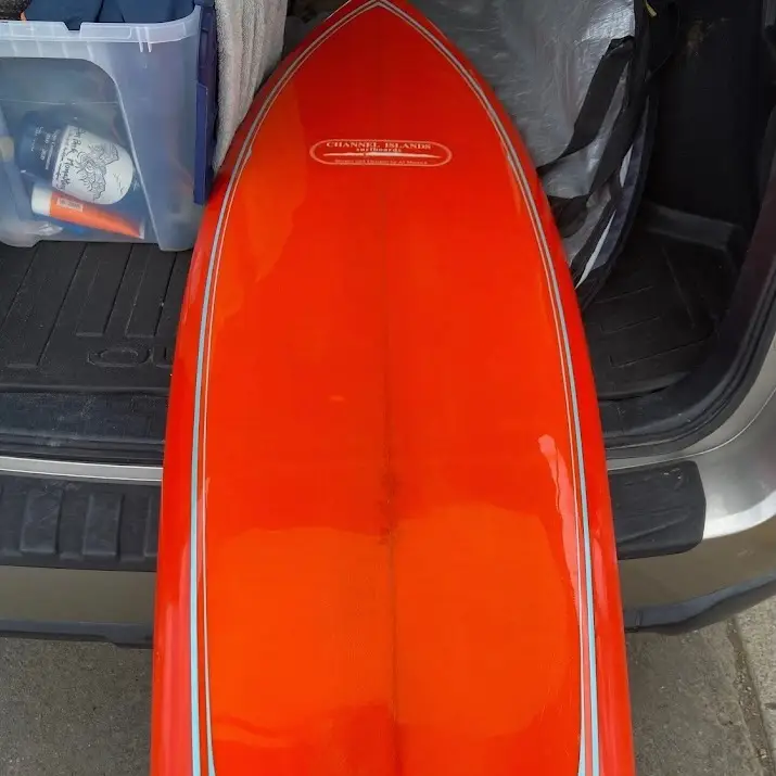 Photo of a customer's polished red surfboard after being repaired by Joe Roper's.